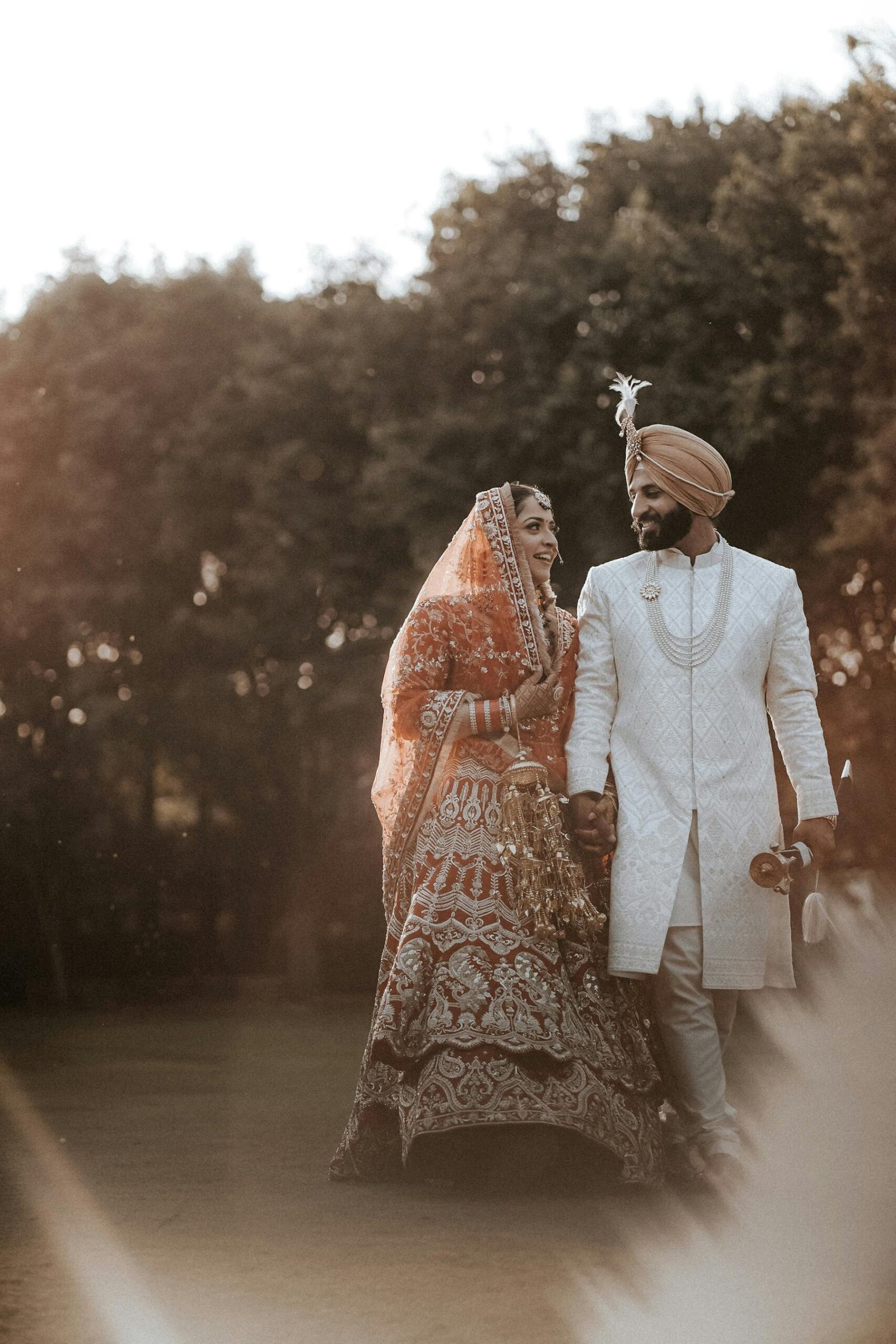 Joyful Indian couple in traditional wedding attire, celebrating love surrounded by nature.