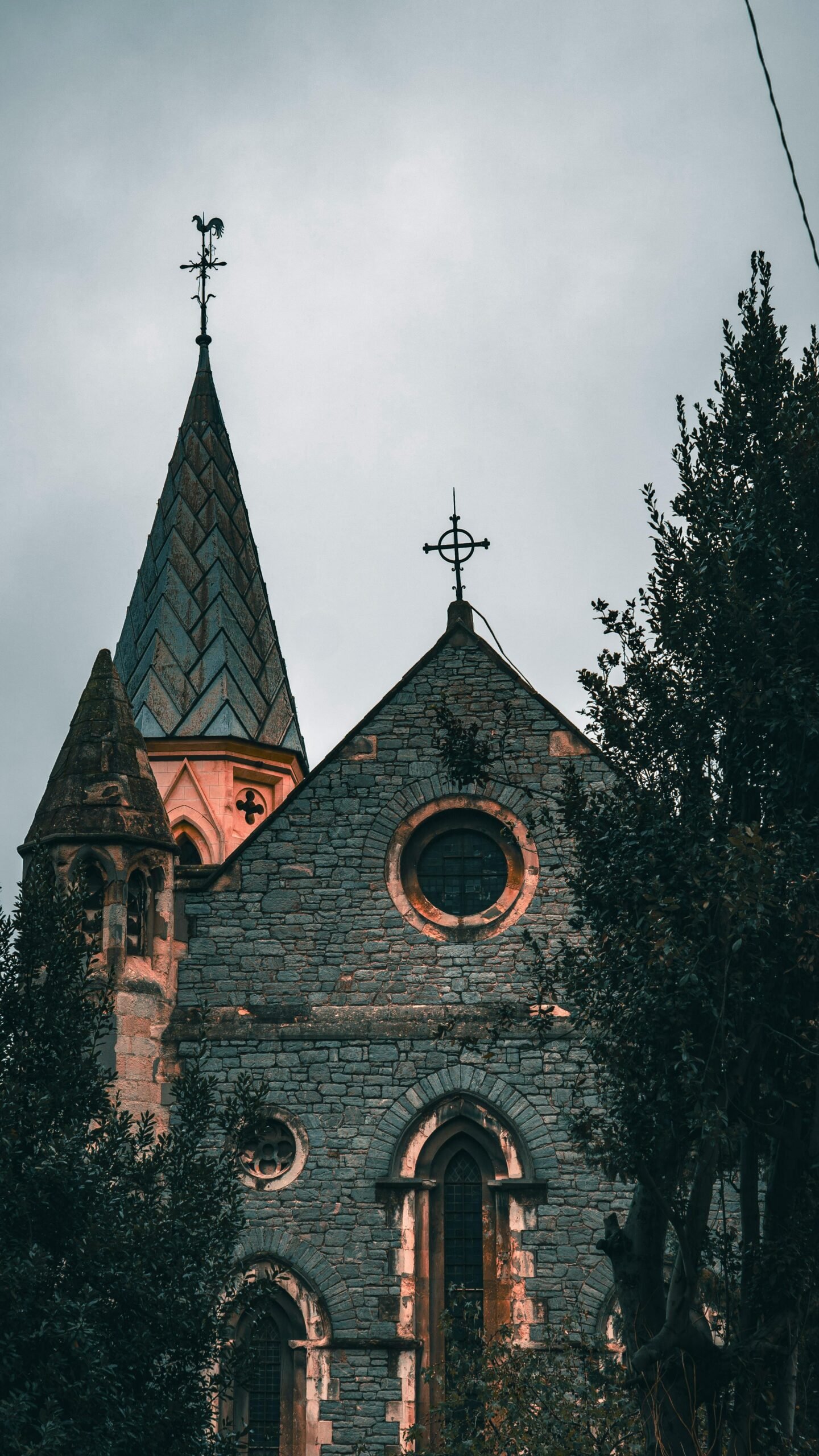 An atmospheric view of a historic stone church featuring gothic architecture surrounded by trees.
